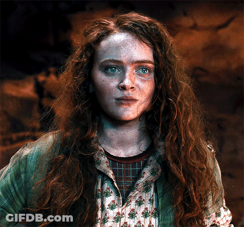 A Woman With Red Hair And Freckles Is Wearing A Green Jacket And A Plaid Shirt GIF