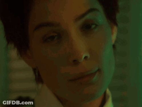 A Woman With Red Hair And Red Lipstick Is Looking At The Camera . GIF