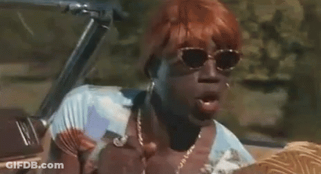 A Woman With Red Hair And Sunglasses Is Sitting In A Convertible Car . GIF