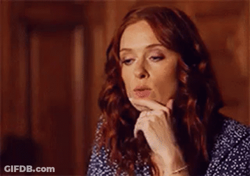 A Woman With Red Hair Is Blowing A Kiss While Holding Her Hand To Her Face . GIF