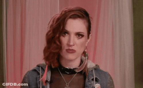 A Woman With Red Hair Is Covering Her Face With Her Hand While Talking On A Phone . GIF