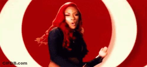 A Woman With Red Hair Is Dancing In Front Of A Red Background . GIF
