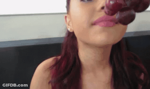 A Woman With Red Hair Is Eating Grapes With Her Mouth GIF