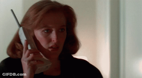 A Woman With Red Hair Is Holding A Cell Phone In Her Hand GIF