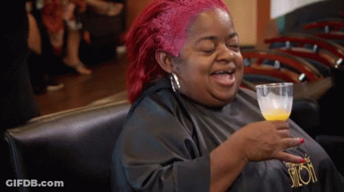 A Woman With Red Hair Is Holding A Glass Of Orange Juice GIF