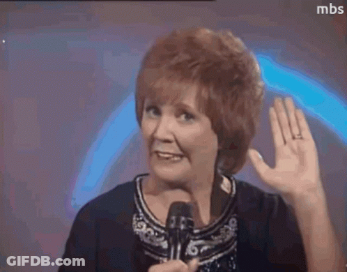 A Woman With Red Hair Is Holding A Microphone And Waving Her Hand . GIF