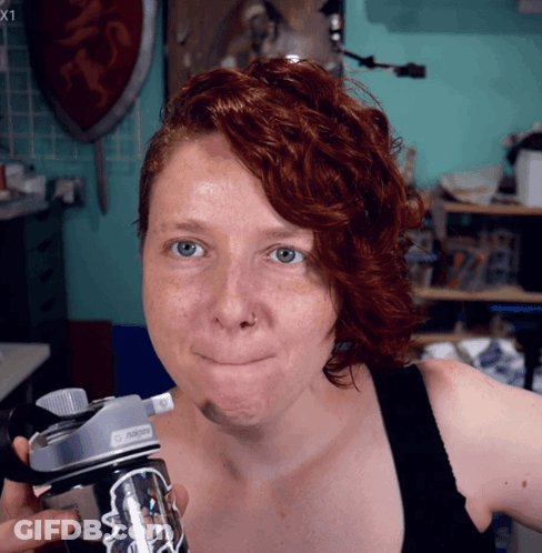 A Woman With Red Hair Is Holding A Nalgene Bottle GIF