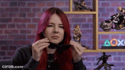 A Woman With Red Hair Is Holding A Pair Of Sunglasses GIF