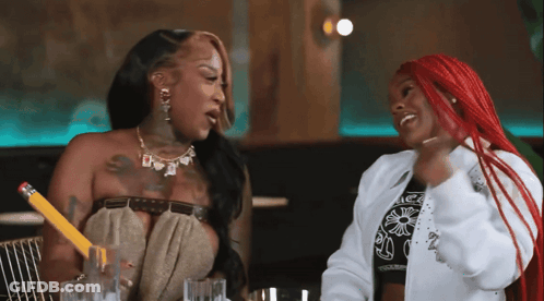 A Woman With Red Hair Is Holding A Pencil While Talking To Another Woman GIF