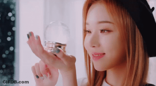 A Woman With Red Hair Is Holding A Snow Globe In Her Hand GIF