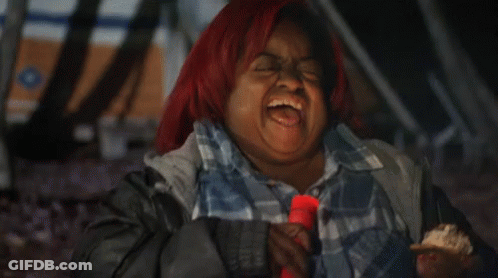 A Woman With Red Hair Is Laughing While Holding A Candle GIF