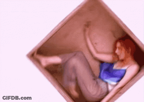A Woman With Red Hair Is Laying In A Box GIF