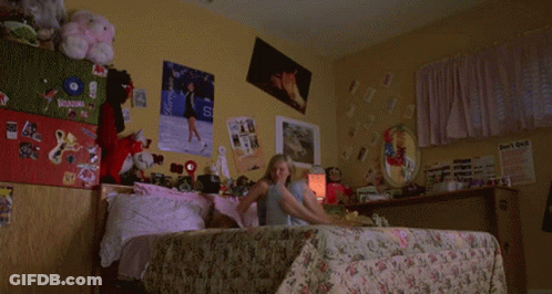 A Woman With Red Hair Is Laying On A Bed In Front Of A Poster That Says ' Gan ' On It . GIF
