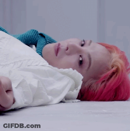A Woman With Red Hair Is Laying On The Floor With A White Shirt On . GIF