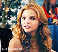 A Woman With Red Hair Is Looking At The Camera GIF