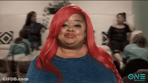 A Woman With Red Hair Is Making A Funny Face In Front Of A Group Of Women . GIF