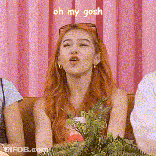 A Woman With Red Hair Is Making A Funny Face While Sitting On A Couch With Other People . GIF