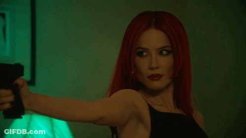 A Woman With Red Hair Is Pointing A Gun At Someone GIF
