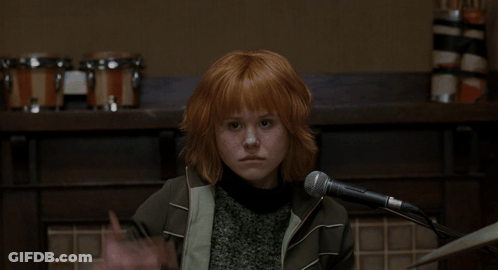 A Woman With Red Hair Is Singing Into A Microphone In Front Of A Sign That Says Ami On It GIF