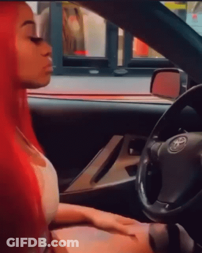 A Woman With Red Hair Is Sitting In A Car With A Toyota Logo On The Steering Wheel GIF