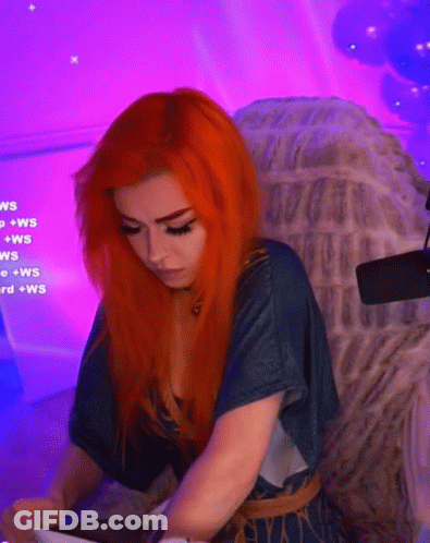 A Woman With Red Hair Is Sitting In A Chair With Purple Lights Behind Her . GIF