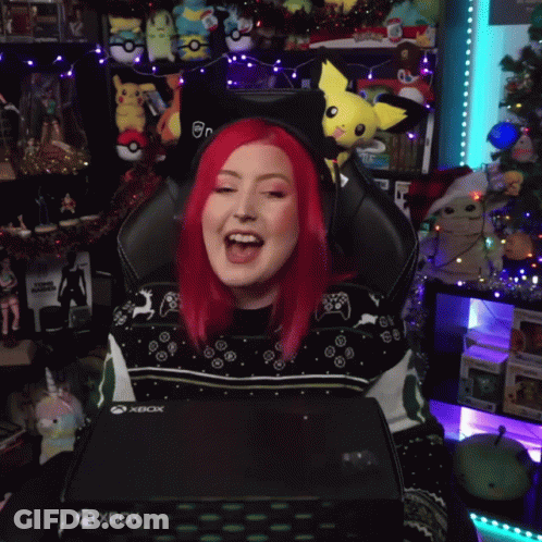 A Woman With Red Hair Is Sitting In A Gaming Chair Holding An Xbox Box GIF