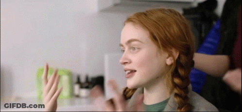 A Woman With Red Hair Is Sitting In A Kitchen With Her Hair In Pigtails . GIF