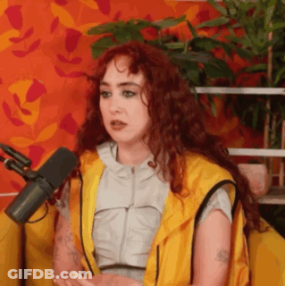 A Woman With Red Hair Is Sitting In Front Of A Microphone And Talking . GIF