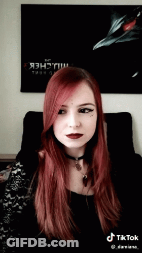 A Woman With Red Hair Is Sitting In Front Of A Poster That Says " Jht " GIF