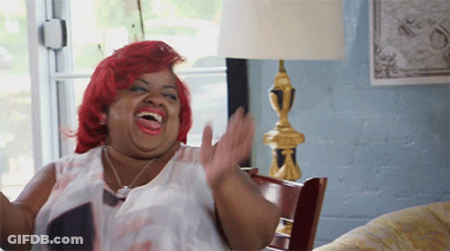 A Woman With Red Hair Is Sitting On A Couch And Laughing GIF