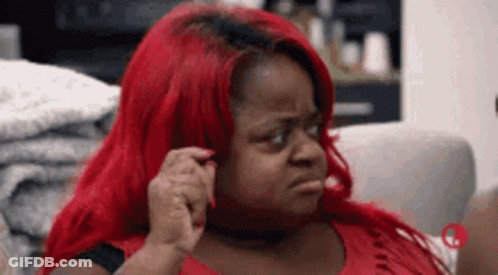 A Woman With Red Hair Is Sitting On A Couch And Making A Face . GIF