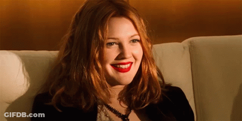 A Woman With Red Hair Is Sitting On A Couch Smiling GIF