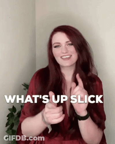 A Woman With Red Hair Is Smiling And Giving A Thumbs Up With The Words What 'S Up Slick Behind Her GIF