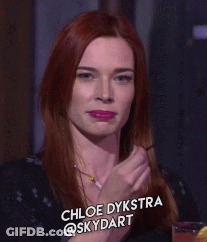 A Woman With Red Hair Is Smiling And Has The Name Chloe Dykstra @Skydart On The Bottom GIF