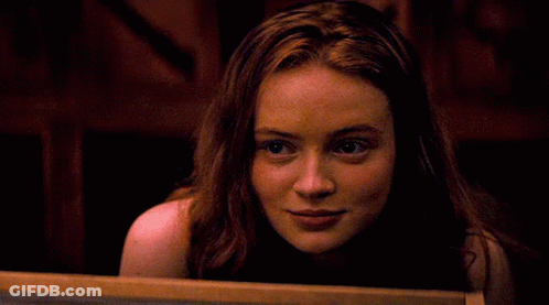 A Woman With Red Hair Is Smiling And Looking At The Camera GIF