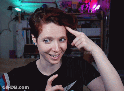 A Woman With Red Hair Is Smiling And Pointing At Her Head GIF