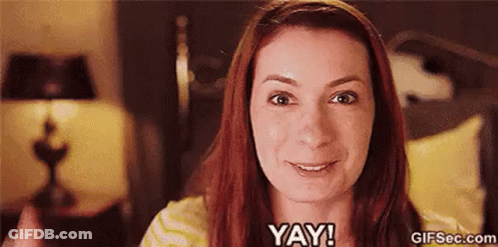 A Woman With Red Hair Is Smiling And Says Yay ! GIF