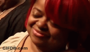 A Woman With Red Hair Is Smiling With Her Eyes Closed And Making A Funny Face . GIF