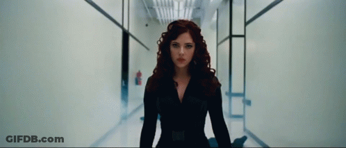 A Woman With Red Hair Is Standing In A Hallway And Looking At The Camera GIF