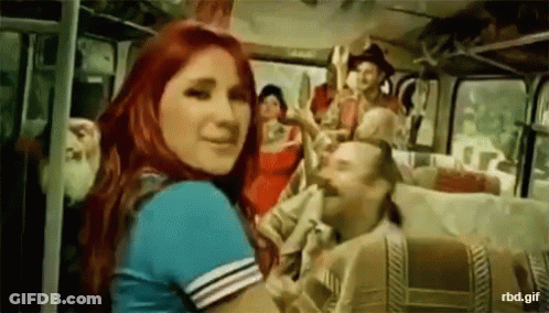 A Woman With Red Hair Is Standing In Front Of A Bus GIF