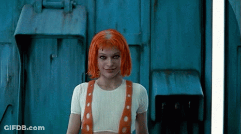 A Woman With Red Hair Is Standing In Front Of A Door GIF