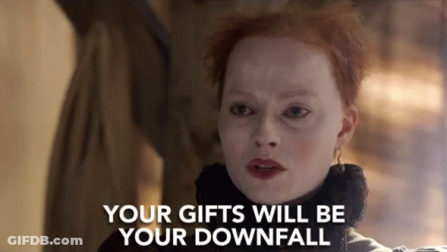 A Woman With Red Hair Is Standing In Front Of A Sign That Says Your Gifts Will Be Your Downfall . GIF