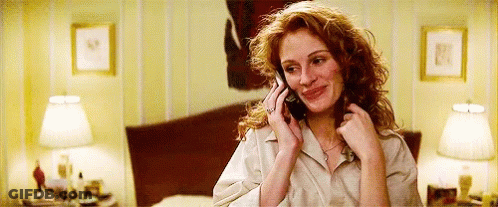A Woman With Red Hair Is Talking On A Cell Phone In A Bedroom . GIF