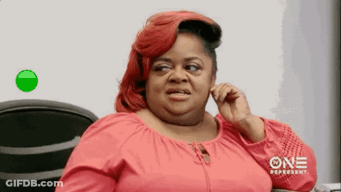A Woman With Red Hair Is Talking On A Cell Phone While Sitting In A Chair . GIF