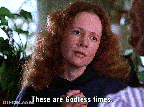 A Woman With Red Hair Is Talking To A Man And Says " These Are Godless Times " GIF