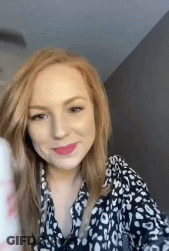 A Woman With Red Hair Is Wearing A Black And White Leopard Print Shirt And Lipstick . GIF