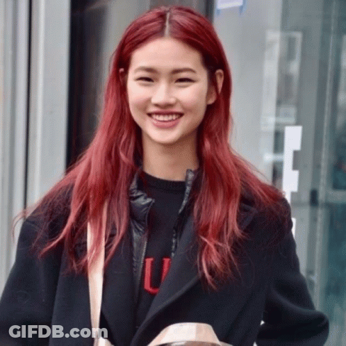 A Woman With Red Hair Is Wearing A Black Jacket And A Black Sweater With The Letter U On It GIF