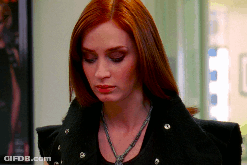 A Woman With Red Hair Is Wearing A Black Jacket And Necklace GIF