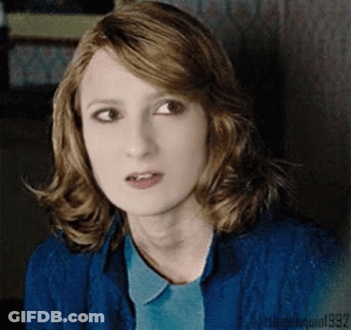 A Woman With Red Hair Is Wearing A Blue Shirt And A Blue Sweater GIF