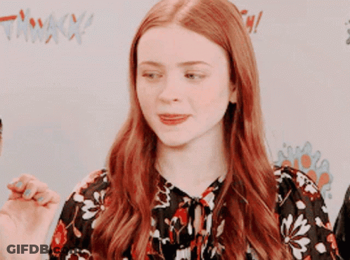 A Woman With Red Hair Is Wearing A Floral Top GIF